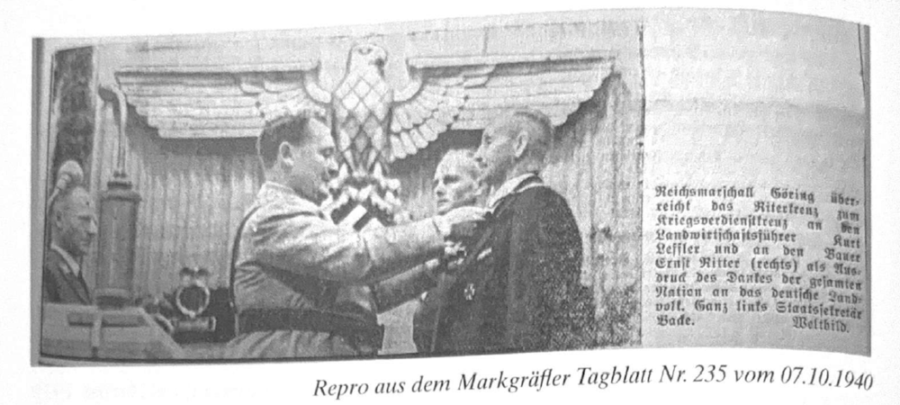 Hermann Göring und Ernst Ritter: Ein Mann in Uniform überreicht einem anderen Mann eine Auszeichnung, im Hintergrund ist ein großes Emblem mit einem Adler und Hakenkreuz zu sehen.